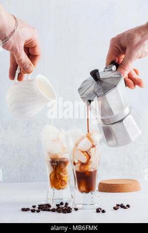 Kaffee und Milch in hohe Gläser mit Eis, schöne und saubere Zusammensetzung gießen Stockfoto