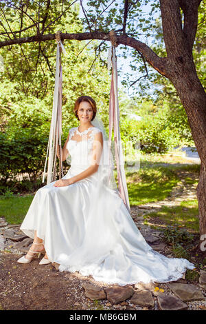 Gerne attraktive Frau auf Schwingen am Sommer Garten Stockfoto