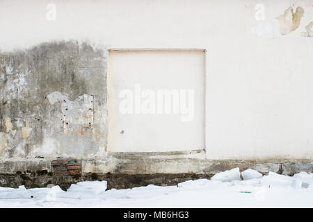 Alte beige Wand mit einer quadratischen Aussparung in der Wand in der das Fenster mit abblätternden Putz für Hintergrund. abgedichtete Fenster. Und Schnee Stockfoto