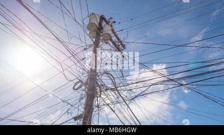 Stromleitungen in der Stadt. Transformatoren und Telefonleitungen gegen den strahlend blauen Himmel. Stockfoto