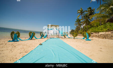 Eine Hochzeit arch geschmückt mit Blumen und großen Wind - Entwicklung von Stoffen an einem tropischen Strand. Philippinen. Bohol. Stockfoto