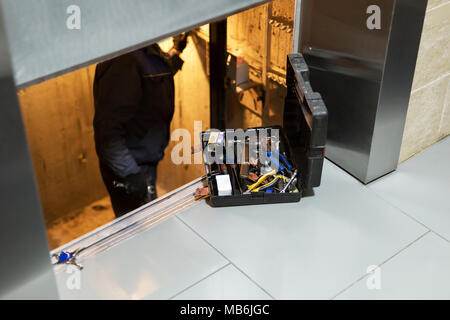 Spezialist der Festsetzung oder Anpassung der Fensterhebermechanismus im Aufzug schaft. Regelmäßige Reparatur, Service und Wartung von Elevator. Stockfoto