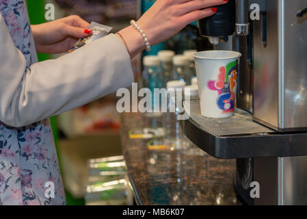 Close up Fotografie. Frauen Hände mit einem heißen Getränk in ein farbiges Papier Cup. Stockfoto