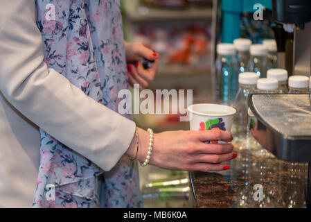 Close up Fotografie. Frauen Hände halten eine farbiges Papier Glas mit einem warmen Getränk. Stockfoto