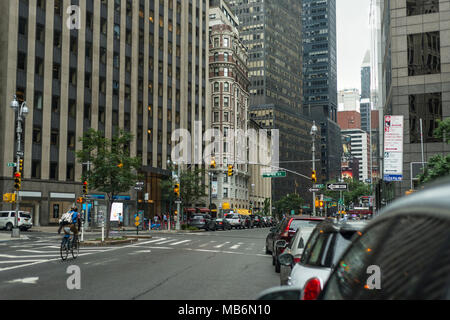 Ein Radfahrer Pedale entlang einer Allee in der Nähe der Kreuzung der W 56th Street in New York, USA, als klassische Gebäude befindet sich zwischen modernen eingeklemmt. Stockfoto