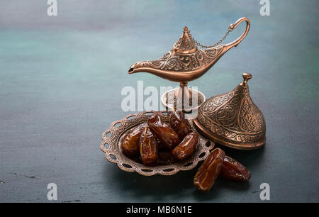 Bronze Platte mit Termine und Aladins Wunderlampe auf dunklem Grün Holz- Hintergrund. Ramadan Hintergrund. Ramadan Kareem. Stockfoto