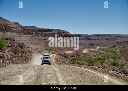 Touristen im 4x4 Autos auf einen Selbstfahrer Reise auf Schotter Straße durch einsame Felsen Berglandschaft im Süden von Namibia, Afrika Stockfoto