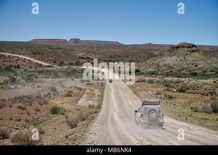 Touristen im 4x4 Autos auf einen Selbstfahrer Reise auf Schotter Straße durch einsame Felsen Berglandschaft im Süden von Namibia, Afrika Stockfoto