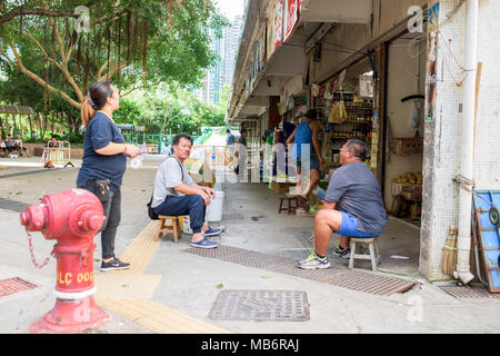 Menschen sitzen vor dem Laden auf den Straßen von Hong Kong Stockfoto