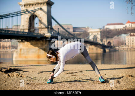 Frau in Sportswear stretching auf Donau Promenade in Budapest, Ungarn Stockfoto