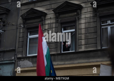 Budapest, Ungarn. 7. April 2018. Eine spontane und fröhlich winkend von einer Dame wie die Menge unter Ihrem Fenster marschierten. Stockfoto