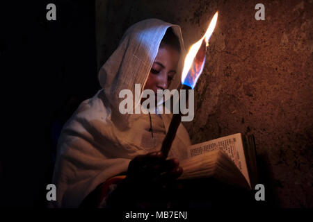 Eine äthiopisch-orthodoxe christliche Pilgerin hält während der Zeremonie des Heiligen Feuers im Kloster Deir El-Sultan, das sich auf dem Dach der Grabeskirche in der Altstadt von Ostjerusalem Israel befindet, eine Kerze in der Hand. Äthiopische Christen gedenken Ereignisse rund um die Kreuzigung von Jesus Christus, die bis zu seiner Auferstehung am Ostern, die in der amharischen Sprache, wird als Fasika, stammt aus dem griechischen Wort Pascha. Stockfoto