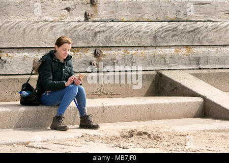 Familie Tag heraus, Crosby Strand, Merseyside. 8. April 2018. UK Wetter. Eine einsame Frau saugt die Frühlingssonne als sitzt sie Entspannen am Meer in Crosby in der Nähe von Liverpool. Credit: cernan Elias/Alamy leben Nachrichten Stockfoto