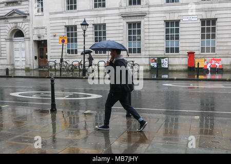 London, Großbritannien. 8. April 2018. Fußgänger schutz vor dem nassen Bedingungen auf Fulham Road, als der Regen nach sonnigen Perioden Credit: Amer ghazzal/Alamy Leben Nachrichten ankommen Stockfoto