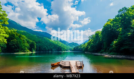 Schönen Bergsee an sonnigen Sommertagen mit geschwollenen Wolken am blauen Himmel, grünen Wald und Boot. Stockfoto