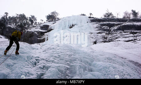 Männliche Bergführer Abseilen aus einem steilen gefrorenen Wasserfall nach einem ice Ausflug klettern Stockfoto