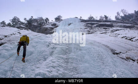 Männliche Bergführer Abseilen aus einem steilen gefrorenen Wasserfall nach einem ice Ausflug klettern Stockfoto