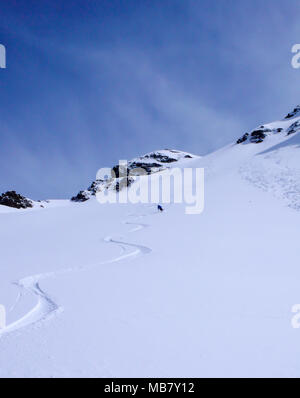 Männliche Skifahrer und frische Spuren in den unberührten Pulverschnee im Backcountry der Schweizer Alpen Stockfoto