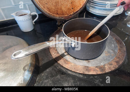 Soße Rühren in einem alten Kochtopf auf einer rustikalen AGA-Herd Stockfoto