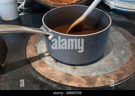 Soße Rühren in einem alten Kochtopf auf einer rustikalen AGA-Herd Stockfoto