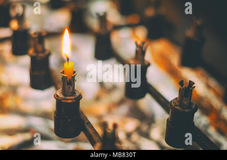 Nahaufnahme von einem einzigen Gebet Kerze fast brannten in einem Kerzenhalter in der Kirche. vintage Filter Effekten. Stockfoto
