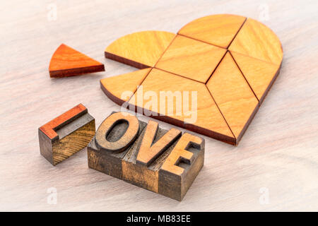 Herz Version von tangram Puzzle mit Liebe Wort in vintage Buchdruck blcoks auf gemasertem Holz Stockfoto