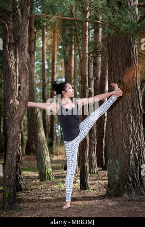 Frau Yoga in einem Wald, verlängerte Hand Zehengriff. Stockfoto