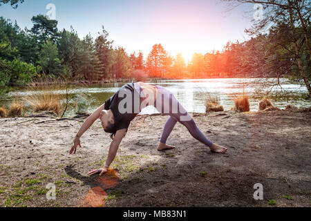 Frau Yoga am See eine wilde Sache darstellen Stockfoto