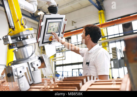 Junge Maschinenbau Arbeitnehmer eine Maschine bedienen für Wicklung Kupferdraht - Herstellung von Transformatoren in einer Fabrik Stockfoto