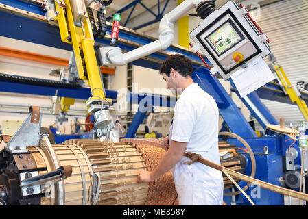 Junge Maschinenbau Arbeitnehmer eine Maschine bedienen für Wicklung Kupferdraht - Herstellung von Transformatoren in einer Fabrik Stockfoto