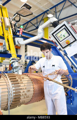 Junge Maschinenbau Arbeitnehmer eine Maschine bedienen für Wicklung Kupferdraht - Herstellung von Transformatoren in einer Fabrik Stockfoto