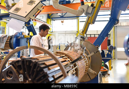 Junge Maschinenbau Arbeitnehmer eine Maschine bedienen für Wicklung Kupferdraht - Herstellung von Transformatoren in einer Fabrik Stockfoto