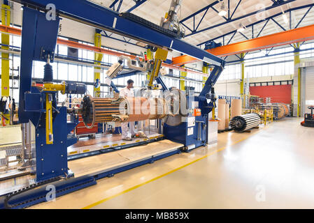 Junge Maschinenbau Arbeitnehmer eine Maschine bedienen für Wicklung Kupferdraht - Herstellung von Transformatoren in einer Fabrik Stockfoto