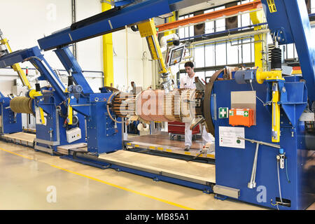 Junge Maschinenbau Arbeitnehmer eine Maschine bedienen für Wicklung Kupferdraht - Herstellung von Transformatoren in einer Fabrik Stockfoto