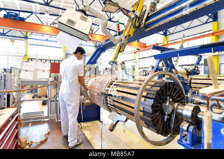 Junge Maschinenbau Arbeitnehmer eine Maschine bedienen für Wicklung Kupferdraht - Herstellung von Transformatoren in einer Fabrik Stockfoto