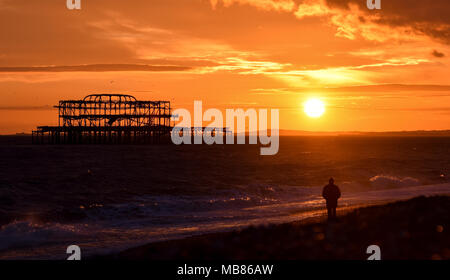 Brighton, Großbritannien - 27 März 2018: der Mann, der den Sonnenuntergang hinter den Ruinen von West Pier von Brighton Beach Stockfoto