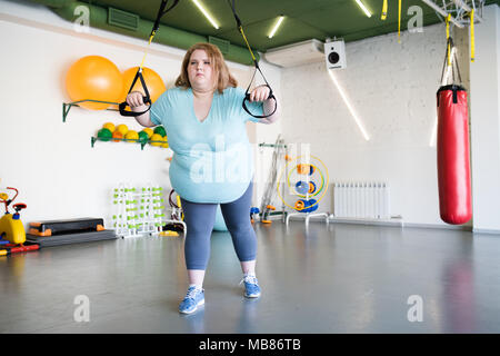 Übergewichtige Frau, die Maschinen in der Turnhalle Stockfoto