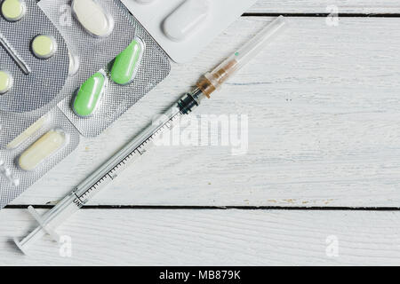 Satz von verschiedenen Tabletten, Kapseln im Blister, Spritze auf weißem Hintergrund aus Holz mit Platz kopieren. Medizin Konzept. Stockfoto