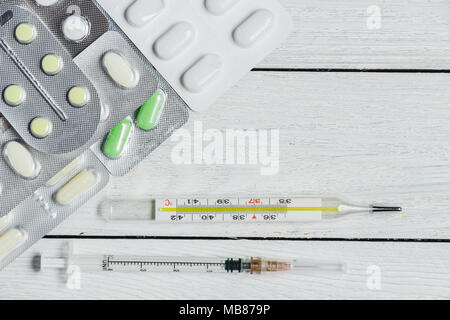 Satz von Tabletten, Kapseln im Blister, Spritze, Thermometer auf Holzuntergrund mit Platz kopieren. Medizin Konzept. Stockfoto