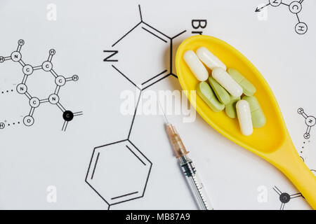 Sortiment von Pillen, Tabletten und Kapseln in Gelb Löffel, die Spritze auf weißem Hintergrund mit der chemischen Formel. Stockfoto