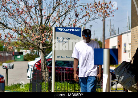 Florence, South Carolina, USA - April 2, 2018: ein Fahrgast Spaziergänge in Richtung Florenz, South Carolina, Amtrak Station das Rauchen einer Zigarette. Stockfoto