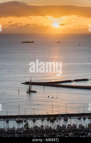 Orange Sonnenuntergang über einem Segelboot Segeln von den Ala Wai kleines Boot Hafen und Magic Island in Honolulu, Hawaii Stockfoto