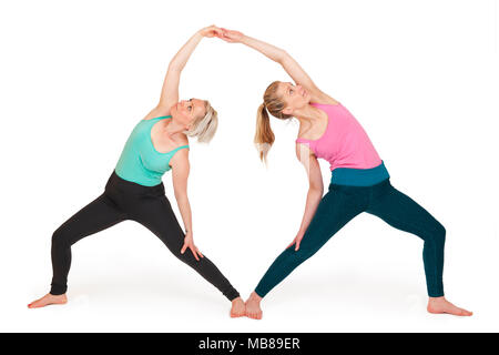 Voller Körper Blick auf Zwei junge blonde Frauen stehen in einer Yoga partner Übungen gegen den weißen Hintergrund mit Licht Schatten. Stockfoto
