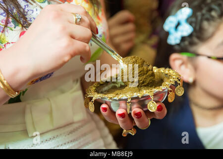 Weibliche Hände dekorativ durch Henna mit Schale gefärbt. Eine Schüssel Halten mit Kokosnuss unter ihren Händen Stockfoto