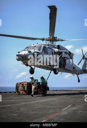 180408 - N-TV 230-2117 SOUTH CHINA SEA (8. April 2018) Segler, dass sich im Bereich nach dem Anbringen einer Ladung Haken zu einem MH-60S Sea Hawk, zu den Indianern der Hubschrauber Meer Combat Squadron (HSC) 6 zugeordnet, auf dem Flugdeck der Flugzeugträger USS Theodore Roosevelt (CVN 71) während einer Auffüllung-auf-See. Theodore Roosevelt wird derzeit für eine regelmäßig geplante Bereitstellung in den USA 7 Flotte Bereich für Maßnahmen zur Erhöhung der Sicherheit des Seeverkehrs und Theater Sicherheit Bemühungen um Zusammenarbeit. (U.S. Marine Foto von Mass Communication Specialist Seaman Bill M. Sanders/Freigegeben) Stockfoto