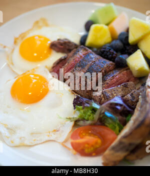 Steak Eier zum Frühstück in der Heimatstadt Diner in Saskatoon, Kanada. Medium Flank Steak, Spiegeleier, Marmor Roggen Toast und Früchte abgebildet. Stockfoto