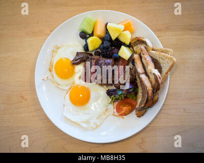Steak Eier zum Frühstück in der Heimatstadt Diner in Saskatoon, Kanada. Medium Flank Steak, Spiegeleier, Marmor Roggen Toast und Früchte abgebildet. Stockfoto
