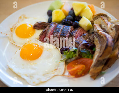 Steak Eier zum Frühstück in der Heimatstadt Diner in Saskatoon, Kanada. Medium Flank Steak, Spiegeleier, Marmor Roggen Toast und Früchte abgebildet. Stockfoto