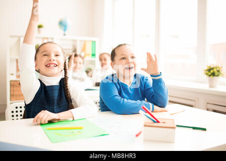 Kinder heben die Hände während des Unterrichts in der Grundschule Stockfoto