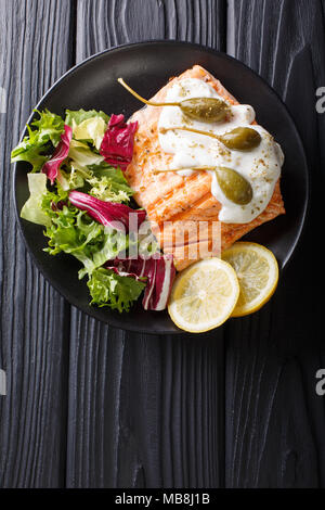 Lachs piccata mit Kapern und Frischer gemischter Salat closeup auf einem Teller. Vertikal oben Ansicht von oben Stockfoto